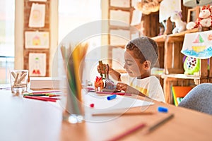 Beautiful african american toddler playing with dinosaurs toy on desk at kindergarten