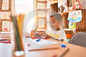 Beautiful african american toddler playing with dinosaurs toy on desk at kindergarten