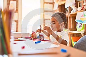 Beautiful african american toddler playing with dinosaurs toy on desk at kindergarten