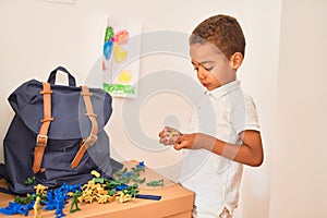 Beautiful african american toddler playing with war miniature figurine at kindergarten