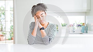 Beautiful african american woman with afro hair wearing casual striped sweater sleeping tired dreaming and posing with hands