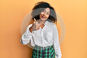 Beautiful african american woman with afro hair wearing scholar skirt doing happy thumbs up gesture with hand