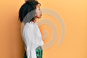 Beautiful african american woman with afro hair wearing scholar skirt looking to side, relax profile pose with natural face with