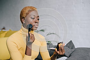 Beautiful african american woman applying powder photo