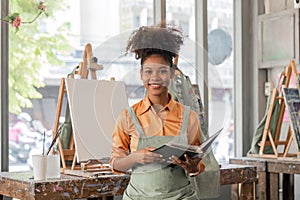 Beautiful African american woman artist smiling confident painting on canvas at art studio