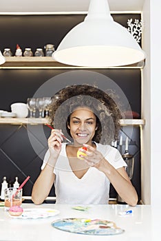 Beautiful African American woman coloring eggs