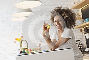 Beautiful African American woman coloring eggs