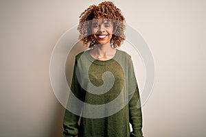 Beautiful african american woman with curly hair wearing casual sweater over white background with a happy and cool smile on face