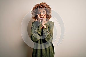 Beautiful african american woman with curly hair wearing casual sweater over white background Tired hands covering face,