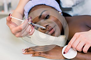 Beautiful African American woman gets injections. Cosmetology. Clinic of Aesthetic Medicine. Fillers, rejuvenation of