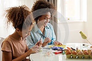 Beautiful African American woman and her daughter coloring Easter eggs