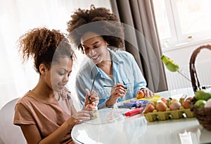 Beautiful African American woman and her daughter coloring Easter eggs