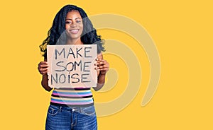 Beautiful african american woman holding make some noise banner looking positive and happy standing and smiling with a confident