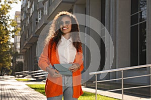 Beautiful African American woman with stylish waist bag on city street, space for text