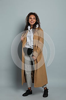 Beautiful African American woman with stylish waist bag on grey background