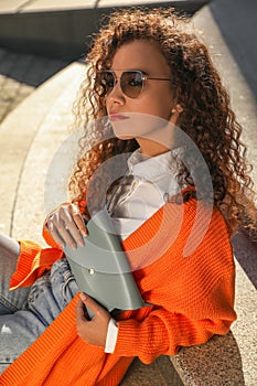 Beautiful African American woman with stylish waist bag on stairs outdoors