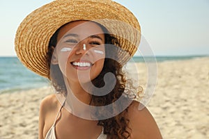 Beautiful African American woman with sun protection cream on face at beach