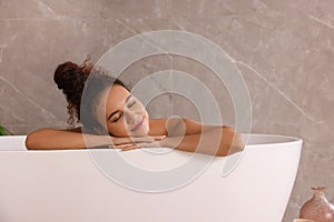 Beautiful African American woman taking bath indoors