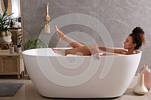 Beautiful African American woman taking bath indoors