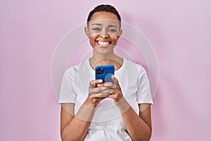 Beautiful african american woman using smartphone smiling with a happy and cool smile on face