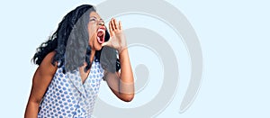 Beautiful african american woman wearing casual summer shirt shouting and screaming loud to side with hand on mouth