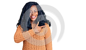 Beautiful african american woman wearing casual  sweater cheerful with a smile of face pointing with hand and finger up to the