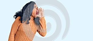 Beautiful african american woman wearing casual  sweater shouting and screaming loud to side with hand on mouth