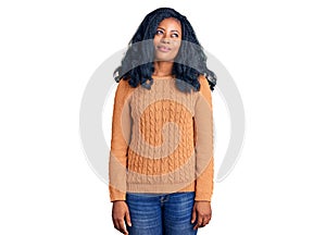 Beautiful african american woman wearing casual  sweater smiling looking to the side and staring away thinking