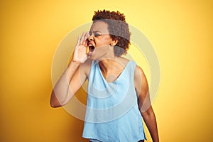 Beautiful african american woman wearing elegant shirt over  yellow background shouting and screaming loud to side with