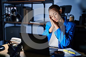 Beautiful african american woman working at the office at night sleeping tired dreaming and posing with hands together while