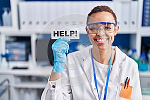 Beautiful african american woman working at scientist laboratory asking for help looking positive and happy standing and smiling