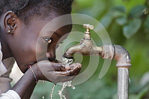 Beautiful African Child Drinking from a Tap Water Scarcity Symbol