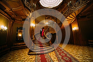 Beautiful african couple going down on vintage stairs. Luxurious theatre interior background