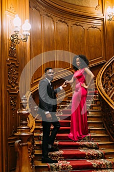 Beautiful african couple posing on the vintage stairs. Luxurious theatre interior background