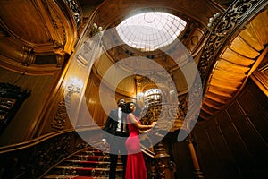 Beautiful african couple posing on the vintage stairs. Luxurious theatre interior background