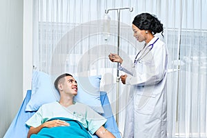 Beautiful african doctor taking care of cacausian teen patient on bed at hospital