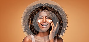 Beautiful african girl applying a cream on cheek