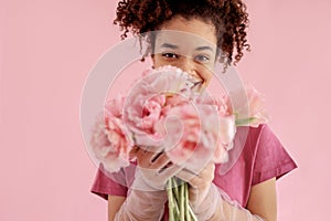 Beautiful african girl holds a bouquet of pink flowers near her face