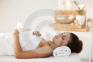 Beautiful african girl lying in spa salon with closed eyes.