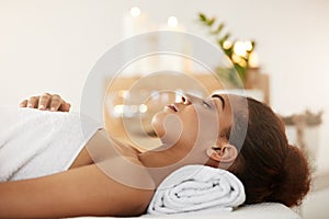 Beautiful african girl lying in spa salon with closed eyes.