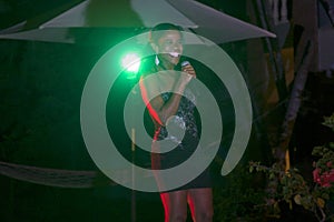 Beautiful African singer woman singing with colorful lights background with her microphone near her mouth