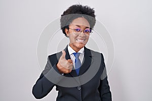 Beautiful african woman with curly hair wearing business jacket and glasses doing happy thumbs up gesture with hand