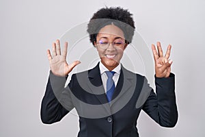 Beautiful african woman with curly hair wearing business jacket and glasses showing and pointing up with fingers number eight