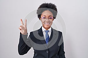 Beautiful african woman with curly hair wearing business jacket and glasses showing and pointing up with fingers number two while