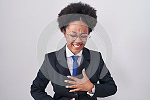 Beautiful african woman with curly hair wearing business jacket and glasses smiling and laughing hard out loud because funny crazy