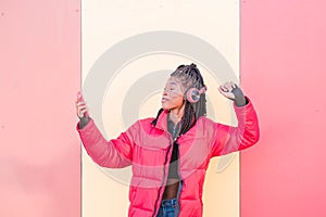 Beautiful African woman dancing outdoors. Black woman listening to music with headphones