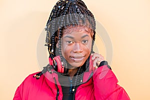 Beautiful African woman looking at camera outdoors. Black woman listening to music with headphones