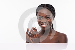 Beautiful african woman with perfect skin holding bottle. Young woman in beauty concept isolated on white. Beauty treatment. Afro