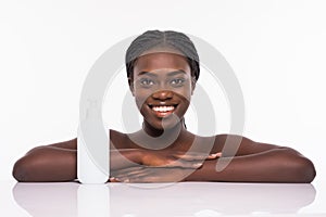 Beautiful african woman with perfect skin holding bottle. Young woman in beauty concept isolated on white. Beauty treatment. Afro