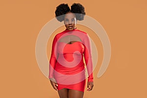 Beautiful african Woman posing in red mini dress, looking at the camera. Afro hairstyle, glamour makeup. Studio Background.